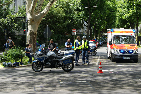 Unfall zwischen einem Auto und einem Polizeimotorrad am Samstagmittag in Wiesbaden. Rettungskräfte versorgen den verletzten Polizisten.