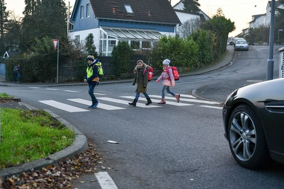 Kinder queren einen Fußgängerüberweg auf dem Weg zur Schule.