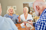Senioren und Seniorinnen spielen gemeinsam Karten und haben Spaß.