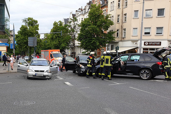 BMW kracht bei Abbiegevorgang auf Kreuzung in Wiesbaden in zwei andere Autos. Drei Personen werden verletzt. Rettungskräfte versorgen die Patienten. Die Polizei leitet den Verkehr um.