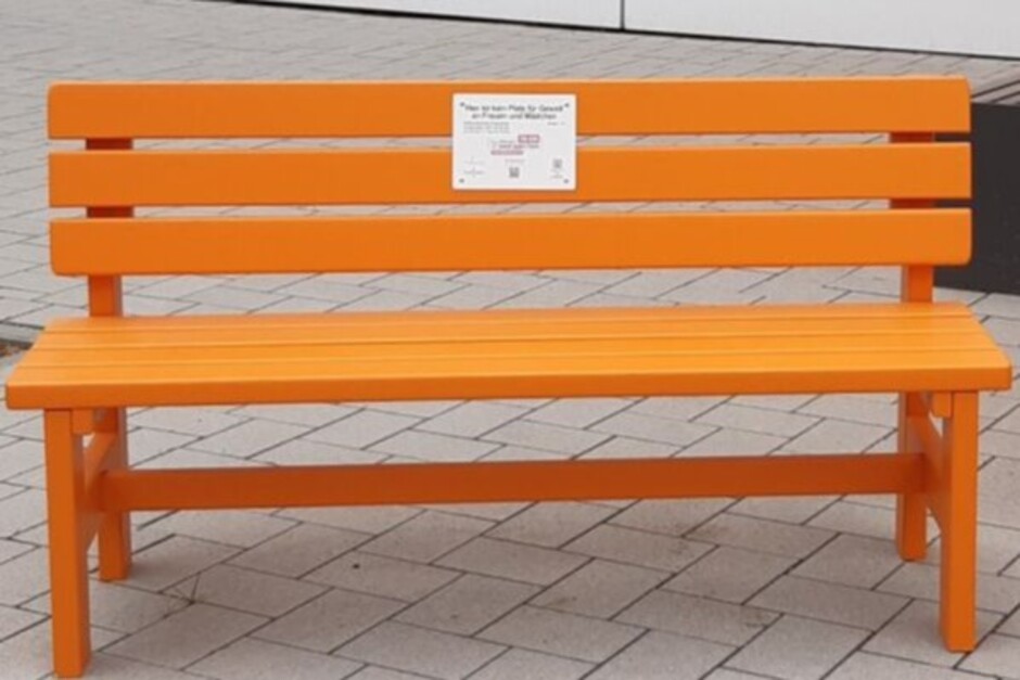 Vor der Wiesbadener Lutherkirche wird eine orangefarbene Bank als Zeichen gegen Gewalt an Frauen aufgestellt.