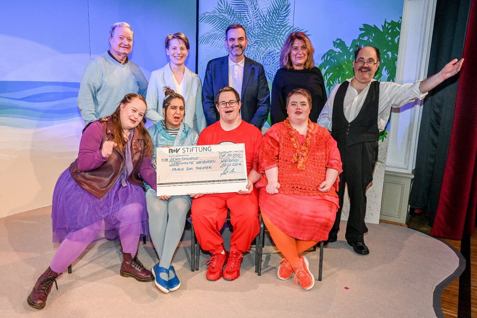 Auch in diesem Jahr unterstützt die R+V „FRANZ das Theater“ mit 10.000 Euro: (vorne sitzend, v.l.) die Schauspielenden Louisa Gagel, Ischtar Akan, Lars Spira und Hanna Bienefeld. Hinten (v.l.): Rainer Neumann (Vorstandsvorsitzender Lebenshilfe Wiesbaden e.V.), Christina Orgnon (R+V), Christoph Loré (Geschäftsführer Lebenshilfe Wiesbaden e.V.), Christiane Jungkenn (Theaterpädagogin FRANZ- das Theater), und Schauspieler Martin Jung.