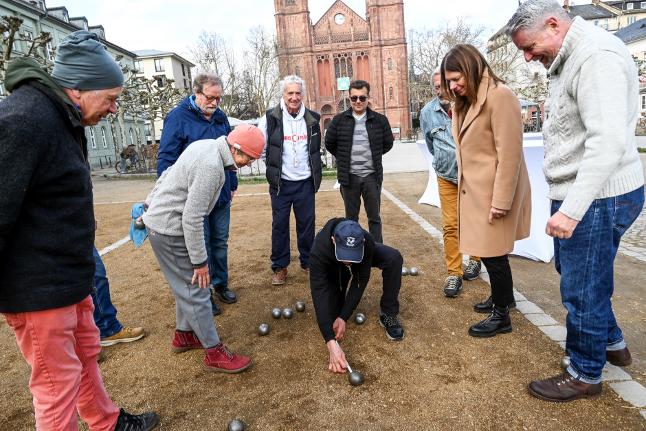 Der Bouleplatz auf dem Luisenplatz in Wiesbaden ist nach der Winterpause wieder geöffnet: Täglich 10–20 Uhr stehen beide Bahnen kostenfrei zur Verfügung, inklusive App-Verleih von Kugeln (Sportbox) und Stühlen (Zuko-Box). Bürgermeisterin Hinninger lobt den Treffpunkt als Begegnungsstätte für alle Generationen.